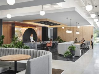 Modern office cafe space with grey banquette and wood tables.